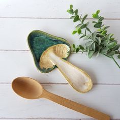 two wooden spoons sitting on top of a table next to a green leafy plant