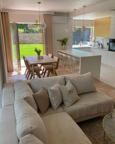 a living room filled with furniture next to a kitchen and an open dining room door