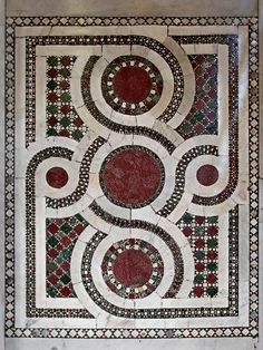 an intricately designed wall hanging in the middle of a room with red and white tiles