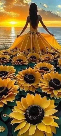 a woman in a yellow dress is surrounded by sunflowers on the beach at sunset