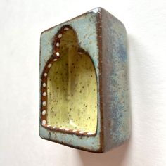 a blue and yellow vase hanging on the wall with a hole in it's center