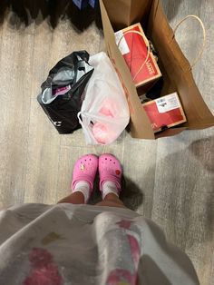 a child's feet in pink shoes next to boxes and bags