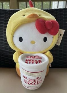 a hello kitty stuffed animal holding a cup of coffee with the lid down on it