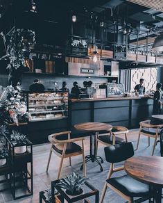 the interior of a restaurant with wooden tables and black chairs, people are sitting at the counter