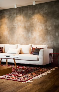 a white couch sitting on top of a wooden floor next to a wall covered in paintings