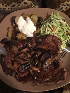 a plate with meat, vegetables and sour cream on it