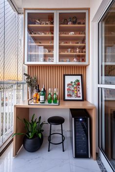 a shelf with bottles and other items on it next to a small stool in front of a window