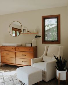 a living room with a dresser, mirror and chair in it's corner area