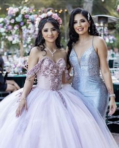 two beautiful women standing next to each other in front of a table with flowers on it