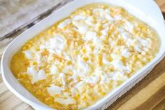 a casserole dish with corn and cheese in it on a wooden table, ready to be eaten