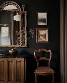 a room with a chair, mirror and pictures on the wall in front of it