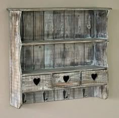 an old wooden shelf with hearts on the bottom and two drawers below, hanging from a wall