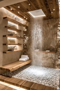 a bathroom with stone walls and wooden flooring has a waterfall in the shower area