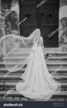 a woman in a wedding dress and veil walking up steps