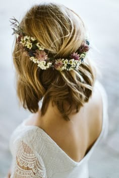 a woman with flowers in her hair wearing a white dress and a floral headpiece