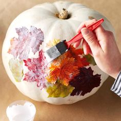 someone is painting a pumpkin with leaves on it