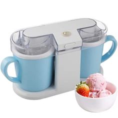 an ice cream maker with two cups and a bowl of strawberries in front of it