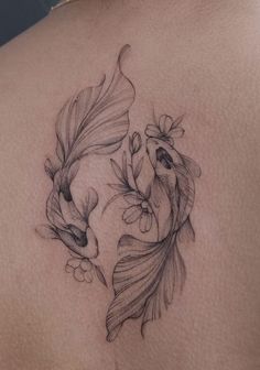 a woman's back with two fish and flowers on it