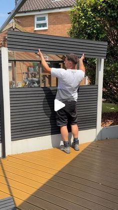 a man standing on top of a wooden deck next to a building with a window