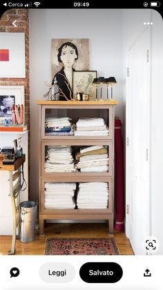 a shelf filled with lots of papers next to a painting on top of a wall