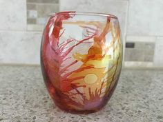 a red glass vase sitting on top of a counter