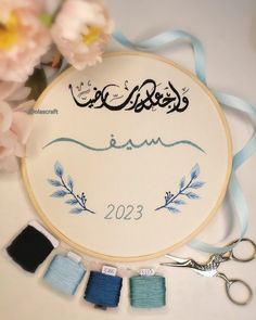 embroidery kit with scissors and thread on table next to pink flowers, peonies and blue ribbon