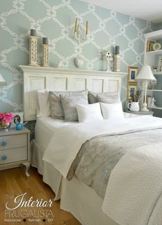 a white bed sitting in a bedroom next to a wallpapered blue and white wall