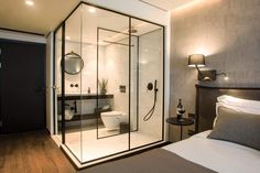 a glass walled shower in a bedroom next to a bed