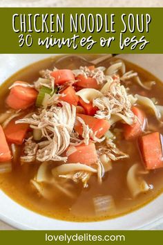 chicken noodle soup in a white bowl with carrots and celery on the side