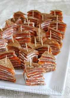 small sandwiches with toothpicks are arranged on a white plate, ready to be eaten