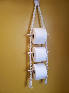 three rolls of toilet paper hanging from a rope on a wall with two other rolls attached to it