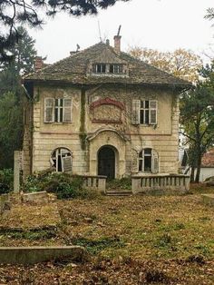 an old abandoned house sitting in the middle of a field with lots of leaves on the ground