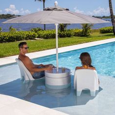 a man and woman sitting under an umbrella next to a pool