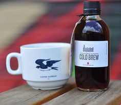 a bottle of cold brew next to a coffee cup