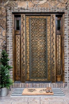 an ornate door on the side of a stone building with potted plants in front