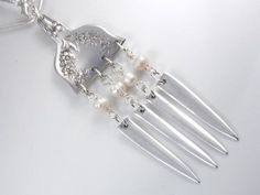 a silver necklace with pearls and forks attached to it