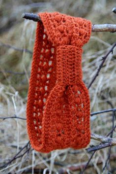 an orange crocheted neck tie hanging from a tree branch