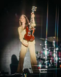 a woman standing in front of a guitar on stage