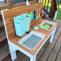 an outdoor play table with ice buckets and cleaning supplies on the back deck area