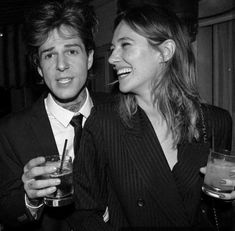 black and white photograph of man and woman holding drinks in their hands, smiling at each other