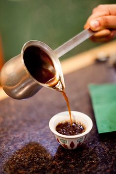 someone pouring coffee into a small cup