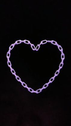 a purple heart shaped object with chains on it's sides, in the dark