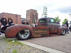 an antique truck is parked on the side of the road with people looking at it