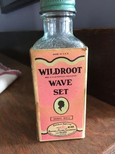 a bottle of wildroot wave set sitting on a wooden table next to a pillow