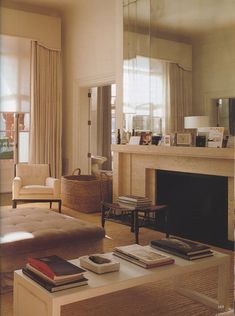 a living room filled with furniture and a fire place in front of a mirror on the wall