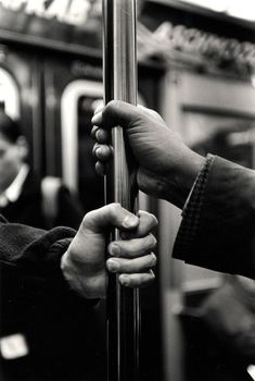 two hands are holding onto the handle of a pole on a subway train or bus