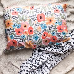 a pillow and blanket laying on top of a bed next to each other with words printed on them