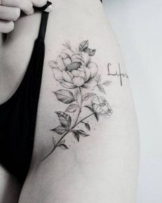 a woman's thigh with a cross and flowers tattoo on her left side ribcage