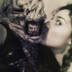 a woman kissing a creepy creature with her mouth open