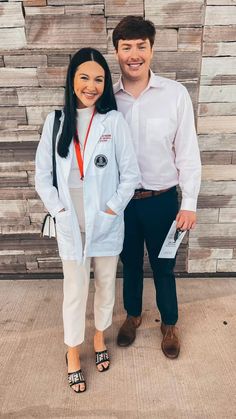 a man and woman standing next to each other in front of a wall with wood planks